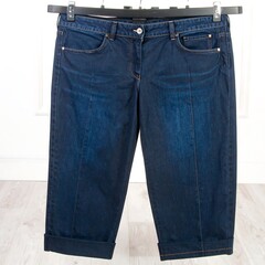 Dark wash cropped denim pants on a hanger