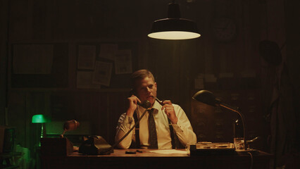 Serious detective working late at night in his office
