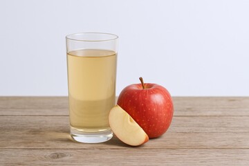 Freshly Pressed Apple Juice in Glass with Whole and Sliced Apples on Wooden Table