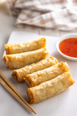 Fried spring rolls with sweet and saur sauce on white table.