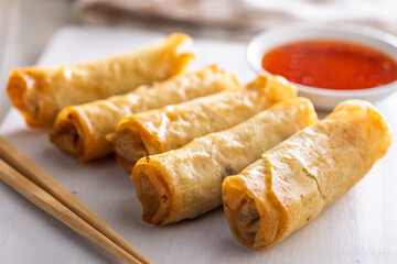 Fried spring rolls with sweet and saur sauce on white table.