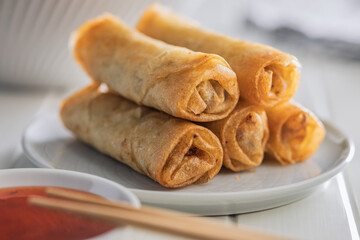 Fried spring rolls on plate on white table.