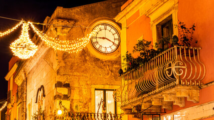 beautiful night view of vintage yellow street building with clock illuminated with holiday decoration