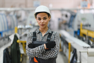 Confident female factory worker posing with crossed arms in production line