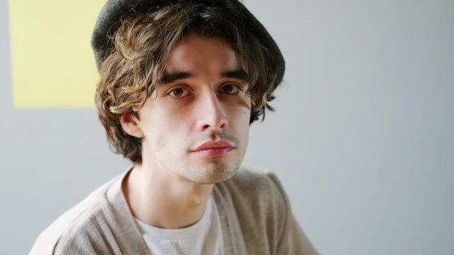 Medium close up portrait of attractive brunette Caucasian man in beret looking at camera
