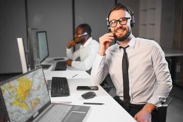 Center of dispatching maintenance. Portrait of men working via headset microphone while sitting on...