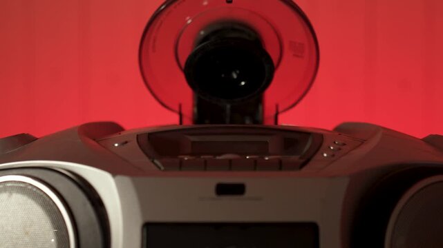 A close-up of a hand inserting a compact disc CD into the open tray of an old or vintage portable CD player