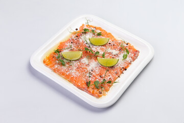 Salmon carpaccio in a plate on a white background.