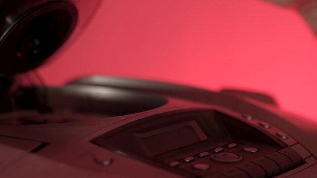 A close-up of a hand inserting a compact disc CD into the open tray of an old or vintage portable CD player