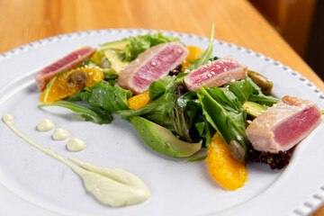 Salad with fried tuna pieces. On a wooden table.