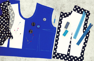 The process of sewing and modeling a dress from blue fabric in the form of a panorama. Pattern of clothes, fabric and accessories on the table.