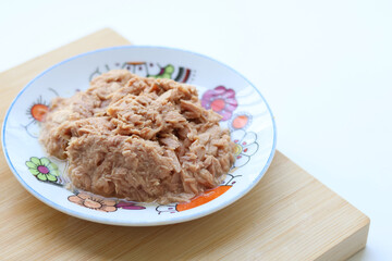 Side view of canned tuna served in a dish on a wooden board