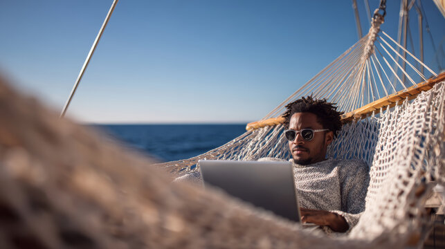 Man relaxing hammock laptop ocean sunglasses sweater outdoor leisure travel remote work vacation peaceful