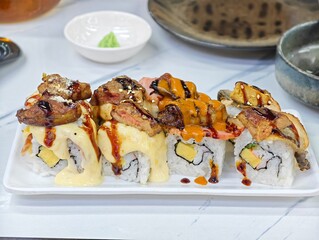 Gourmet sushi rolls topped with foie gras and beef on a white plate, delicious fusion cuisine