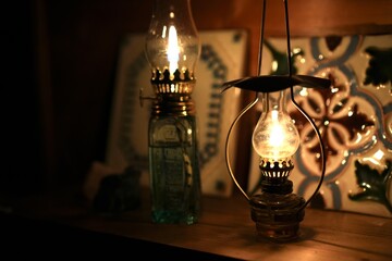 Two oil lamps in a dark room with decorative interior tiles in the background