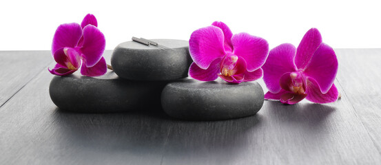 Acupuncture needles, orchid flowers and spa stones on grey wooden table against white background, closeup