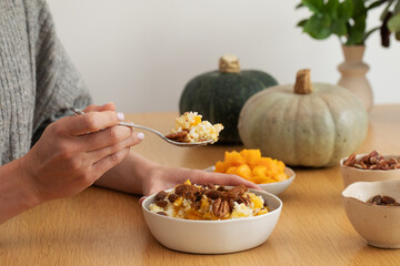 A woman enjoys an autumn breakfast of rice and millet porridge with pumpkin. Pumpkin dish