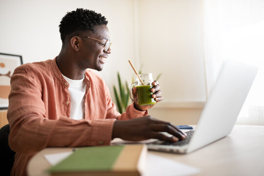 Freelancer working from home drinking green smoothie and using laptop