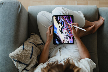 Woman using digital tablet on couch, top view photo