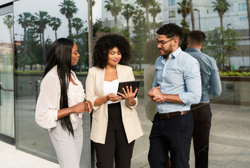 Multiracial diverse business team using a digital tablet discussing a project outside office