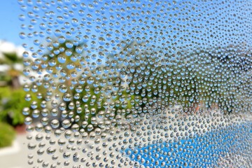 Water droplets on a window, reflecting a blurry outdoor scene