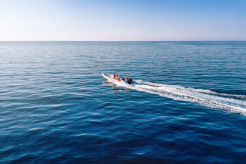 Aerial side view of a RIB speedboat cruising over the calm ocean with copy space