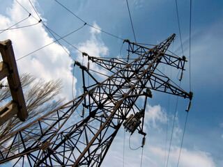 Electricity pylon tower 110 kV. A low-angle view looking up at a steel lattice electrical transmission tower against a cloudy blue sky, high-frequency barrier.