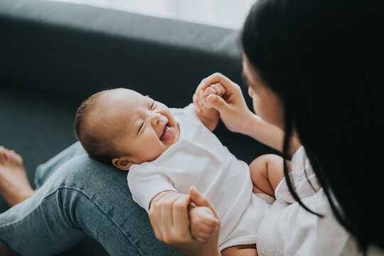 Happy young mother and little baby girl smile and laugh while playing together at home. Motherhood