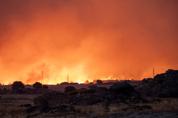A Massive Wildfire Raging Under a Glowing Orange and Red Sky at Night.