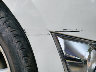 Close-up of a damaged white car bumper with a tire.