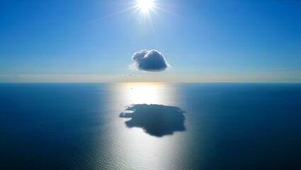 A solitary cloud floats above a still ocean under a bright sun, creating a mirror image effect.
