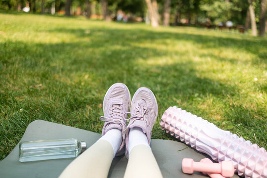 Sports shoes sneakers, dumbbells, yoga mat and bottle of water on fresh green grass. Sport equipment pov view. Concept healthy lifestyle, sport and diet.