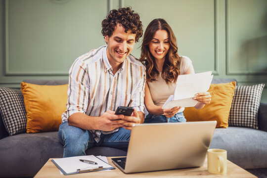 Couple discussing home finance while checking bills. They are checking financial documents and calculating family budget in living room.