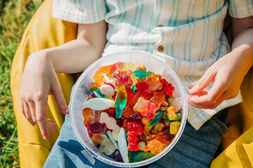 Child holding candy box on bean bag outdoors during birthday party