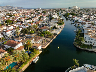Empuriabrava, Spain - 31 December 2023: Aerial view of canals snaking through the town, lined with bright white villas and lush greenery under a soft, diffused light.