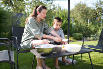 Woman and a kid cooking and eating inthe backyard