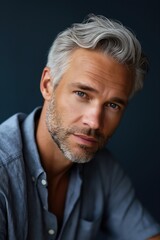 Obraz premium Mature caucasian male with gray hair in thoughtful pose against dark background