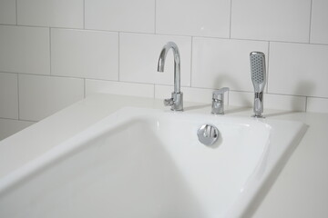 Modern white bathroom sink with chrome faucet and shower head
