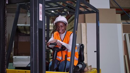 african american Female warehouse worker driving forklift and smiling at camera - Powered by Adobe