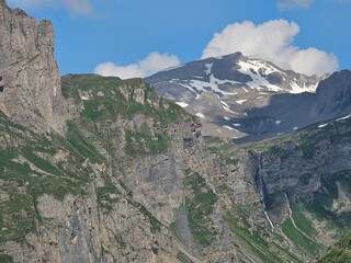 La Thuile, Val D'Aosta, July 02 2025: Panoramic view to the alps, beautiful green landscape reflected in a small natural lake. Beautiful blue sky with some clouds. Mountains with a little snow. Aerial