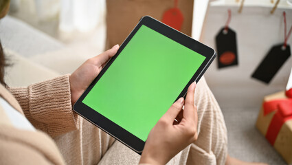 Person holding tablet with green screen for christmas holiday design.