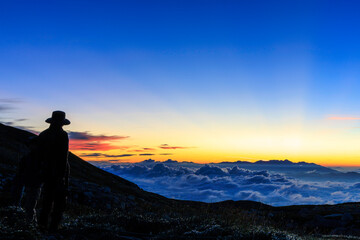 Fototapeta premium 雲海と夜明け前の空を撮影する登山者のシルエット