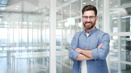 Portrait of smiling successful businessman standing with crossed arms in a business office. Confident happy manager looking at camera. Empty copy space for writing text. Template for advertising
