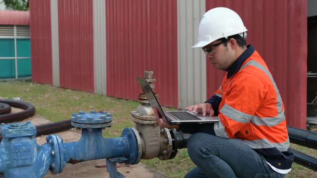 Engineer or plumber working at industrial water supply pipeline in factory, inspecting main water line, repairing system, checking meter reading, ensuring maintenance, safety, and utility management.