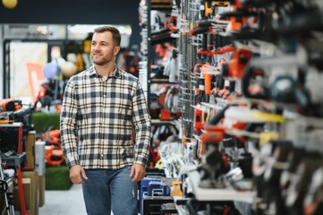 A male buyer chooses power tools in a hardware store. A large selection of tools