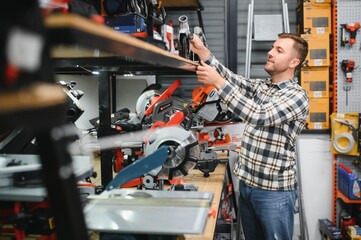 A male buyer chooses power tools in a hardware store. A large selection of tools