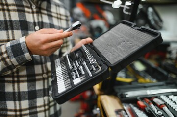 A male buyer chooses a toolbox in a hardware store. A large selection of tools.