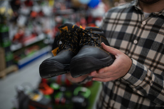 a man in a hardware store chooses safety shoes for construction work