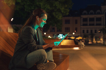 Urban woman working late outdoors on city street using her digital tablet