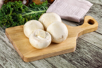 White champignon mushrooms heap over board
